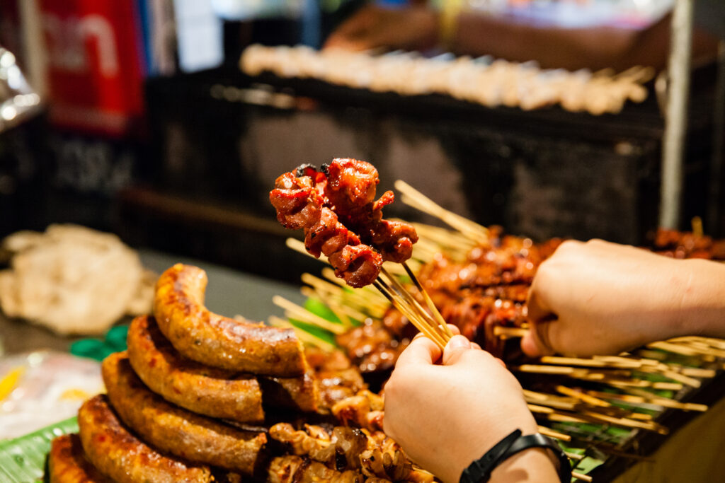 Mann kauft aufgespießt gegrilltes Schweinefleisch