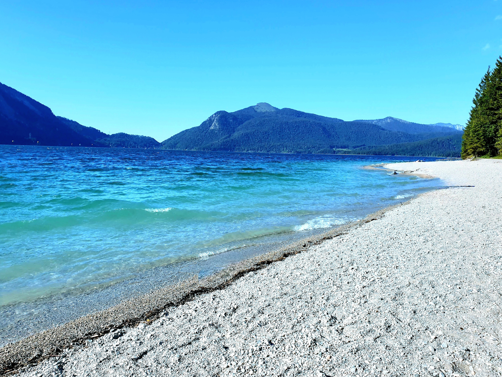 Der Walchensee mit einem schönen Strand und Blick auf Berge und Wälder