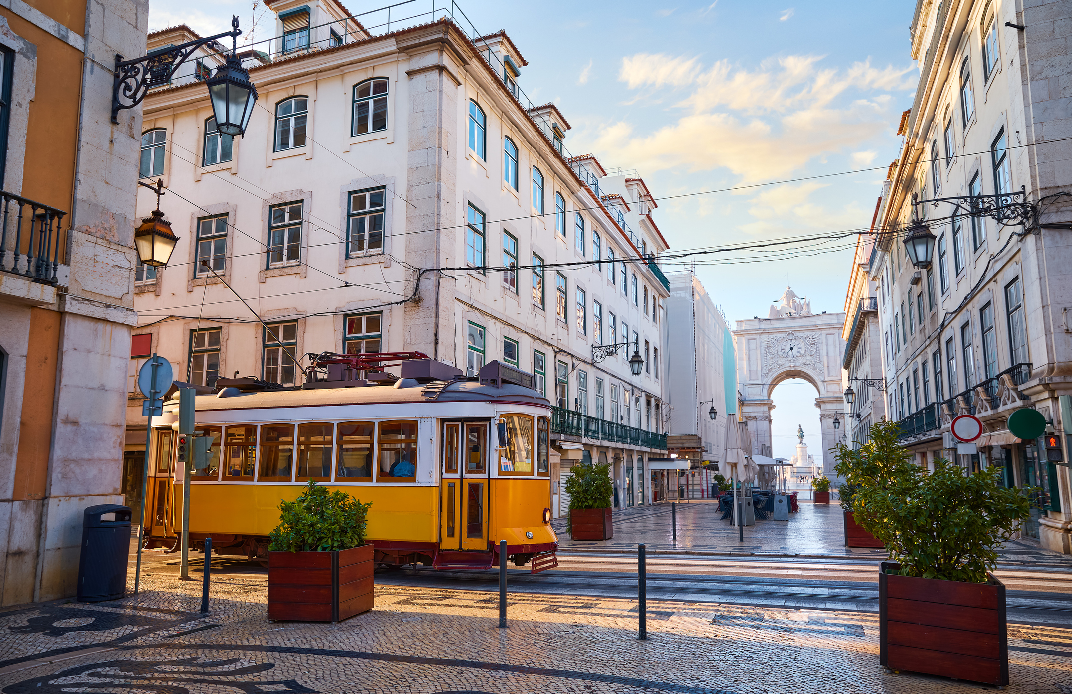 Die typisch gelbe Retro-Straßenbahn und der Triumphbogen von Lissabon