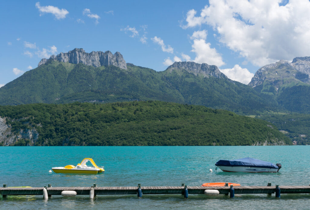 Einige Touristenboote auf dem Lac d'Annecy in Südfrankreich vor den französischen Alpen