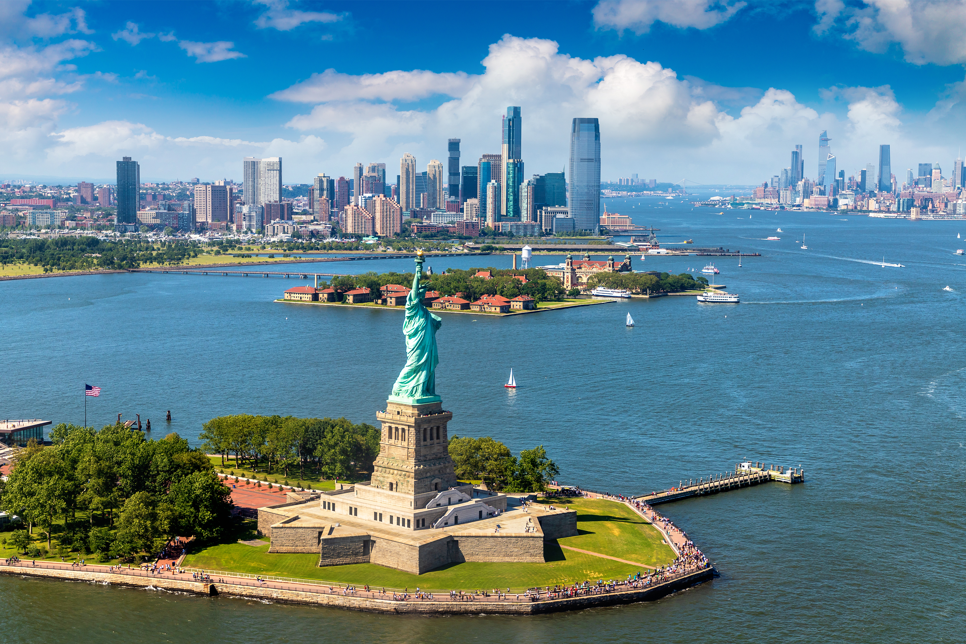 Freiheitsstatue mit Blick auf Manhattan Skyline bei klarem Himmel, Panoramaaufnahme.