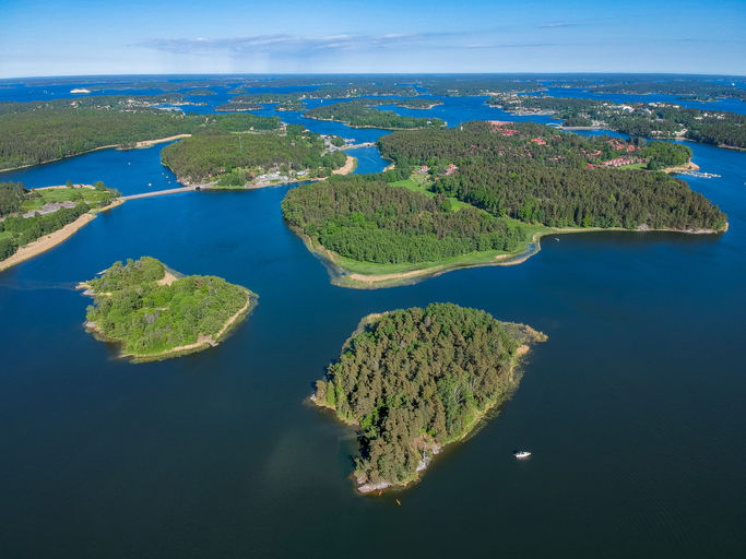 Luftaufnahme mit vielen kleinen Inseln, typischen Häusern und Wasserwegen im Stockholmer Schärengarten.