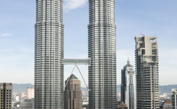 Petronas Towers in Kuala Lumpur aus der Nähe, Blick nach oben auf die Zwillingstürme bei Tageslicht.