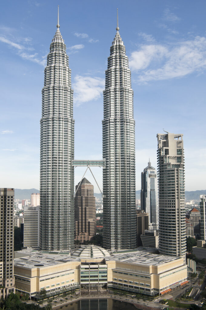 Petronas Towers in Kuala Lumpur aus der Nähe, Blick nach oben auf die Zwillingstürme bei Tageslicht.