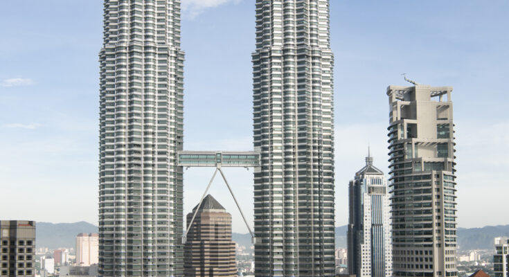 Petronas Towers in Kuala Lumpur aus der Nähe, Blick nach oben auf die Zwillingstürme bei Tageslicht.