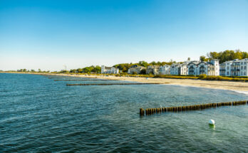 Blick auf den Ostseestrand von Heiligendamm mit Seebad-Villen und Buhnen im Wasser.