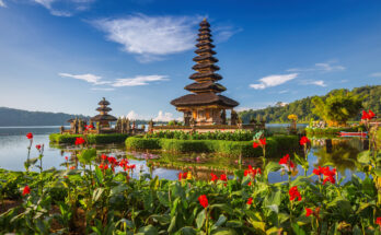 Pura Ulun Danu Bratan auf Bali, Wassertempel am See mit farbenfrohen Blumen im Vordergrund.