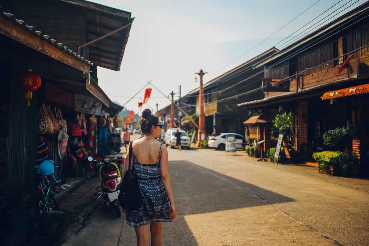 Touristin spaziert durch die Old Town auf Koh Lanta, Thailand, vorbei an traditionellen Holzhäusern, kleinen Geschäften und bunten Dekorationen.