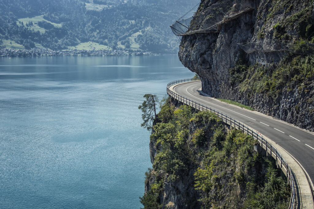 Kurvige Uferstraße schlängelt sich entlang einer steilen Felswand mit Blick auf den Vierwaldstättersee in der Schweiz.