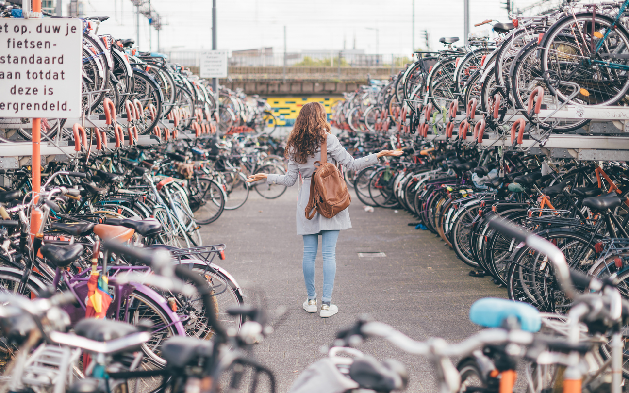 Frau steht zwischen hunderten geparkten Fahrrädern an einem großen Fahrradparkplatz in Eindhoven, Niederlande.