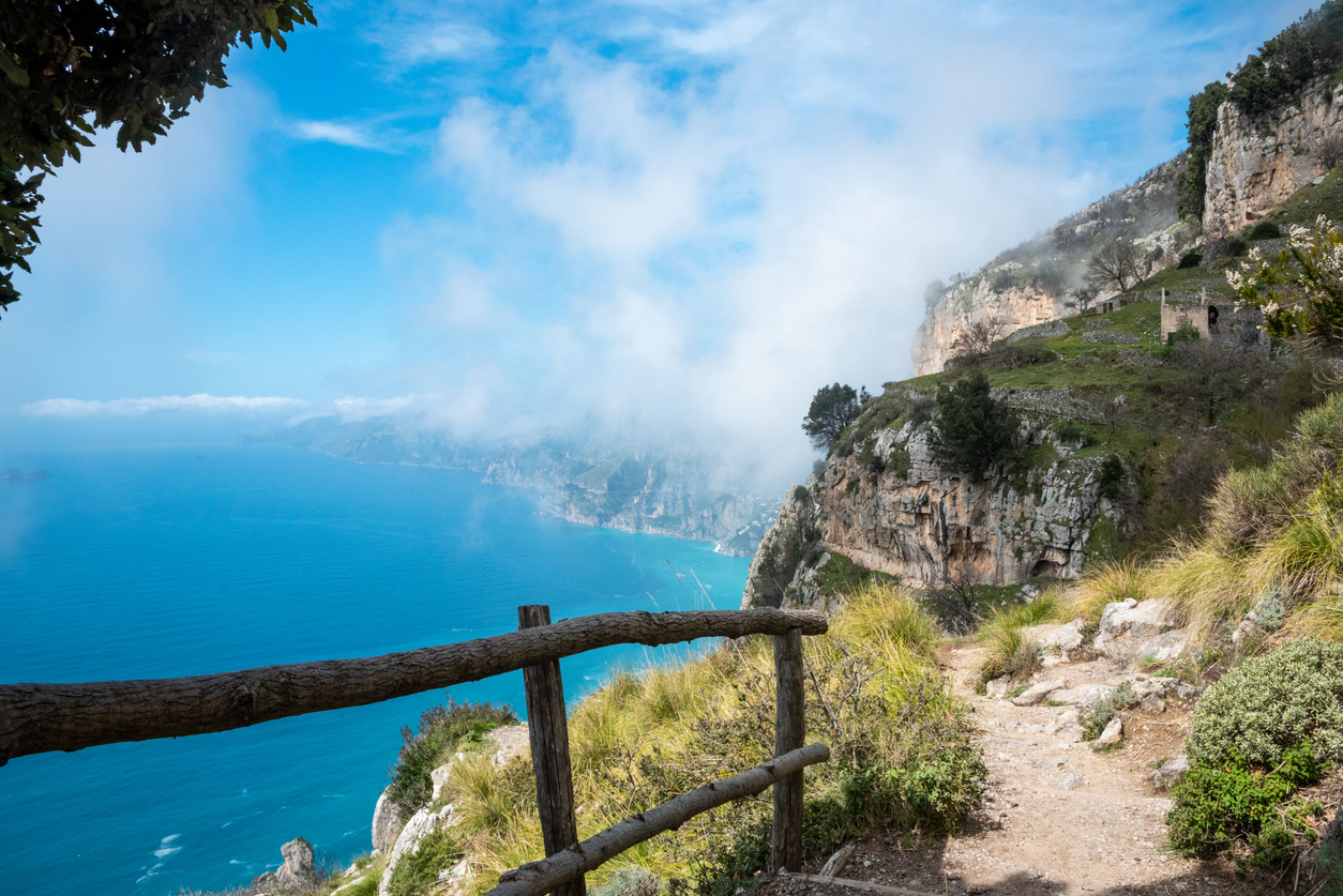 Atemberaubender Blick vom Wanderweg Sentiero degli Dei an der Amalfiküste, mit felsigen Klippen, Meerblick und leichtem Nebel.