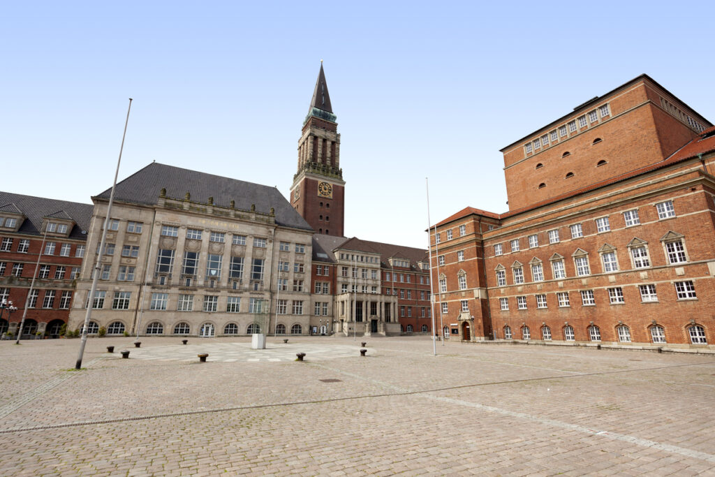 Rathausplatz in Kiel mit Rathaus, Uhrturm und Opernhaus bei klarem Himmel.