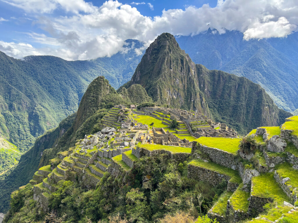 Blick auf die Ruinen der antiken Inkastadt Machu Picchu in Peru, umgeben von den majestätischen Anden und sattem Grün.