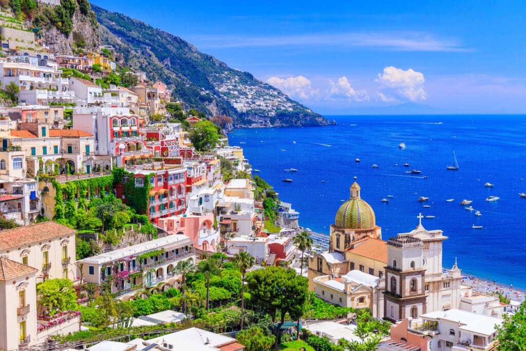 Panorama von Positano an der Amalfiküste in Italien mit bunten Häusern, der Kirche Santa Maria Assunta und dem tiefblauen Mittelmeer.