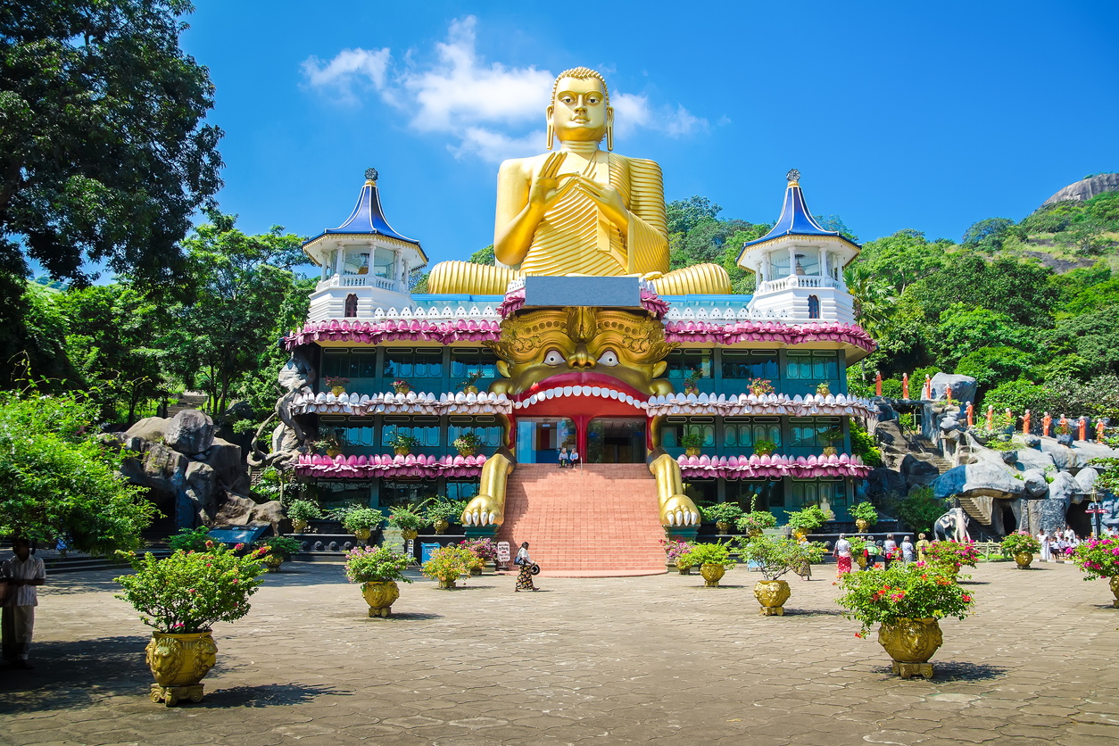 Goldene sitzende Buddha-Statue vor dem Eingang des Höhlentempels von Dambulla in Sri Lanka.