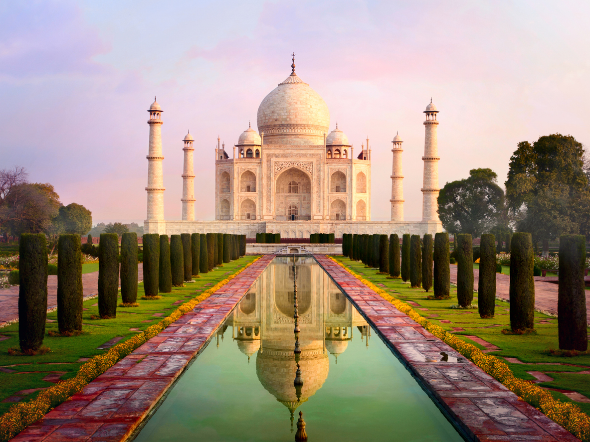 Das Taj Mahal in Agra, Indien, bei Sonnenaufgang mit Spiegelung im Wasserbecken.