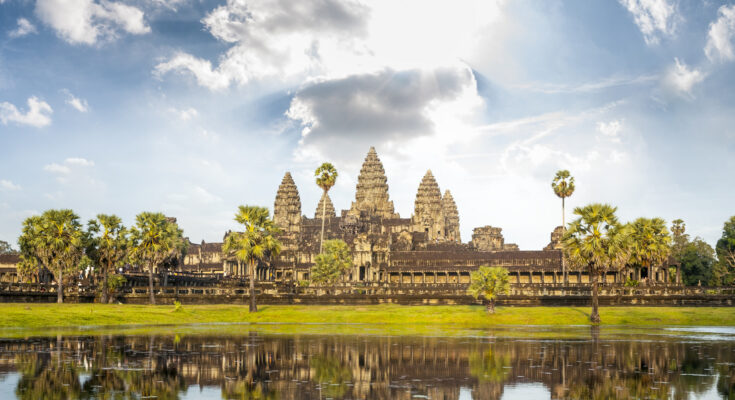 Die beeindruckende Tempelanlage Angkor Wat in Kambodscha, vor einem ruhigen See mit Spiegelung der Türme im Wasser.