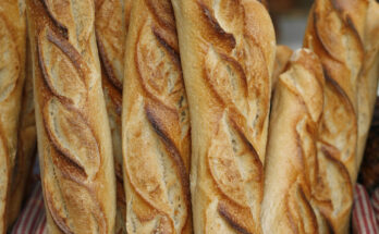 Frisch gebackene französische Baguettes in einem Weidenkorb mit rot-weiß kariertem Stoffeinsatz, goldbraun gebacken und knusprig.
