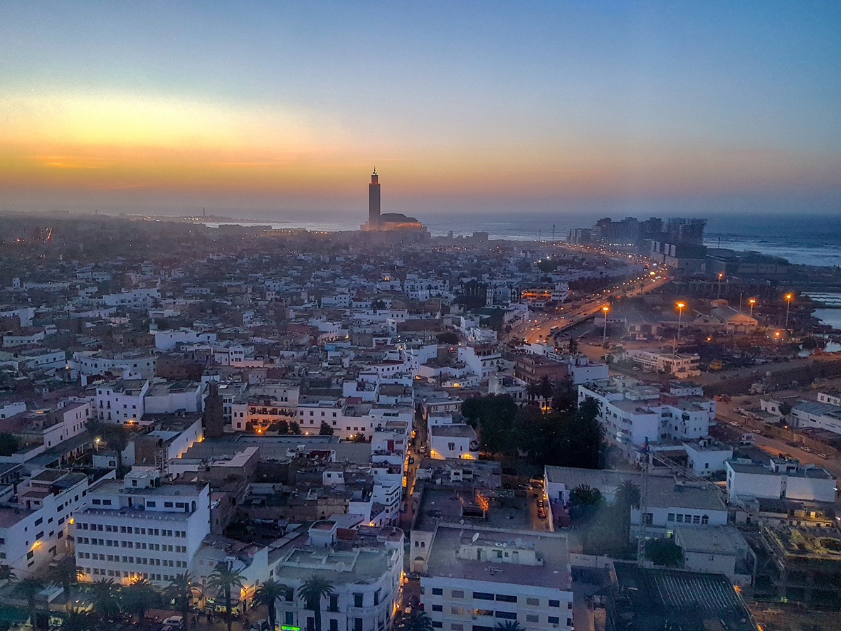 Casablanca bei Sonnenuntergang mit Hassan-II-Moschee, Küstenstraße und Atlantik im Hintergrund.