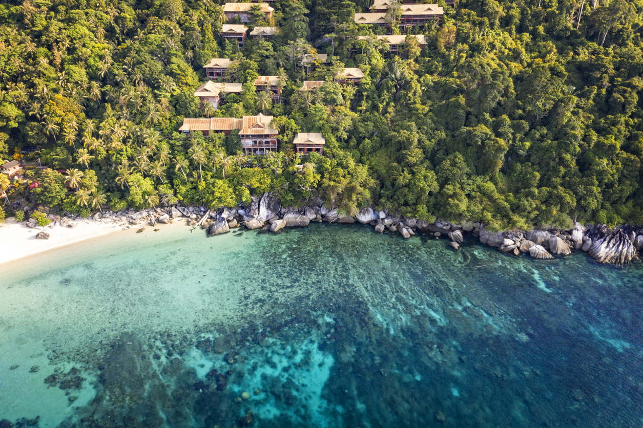 Luftaufnahme von Tioman mit Dschungel, Strand, Felsen und türkisblauem Meer samt Riff