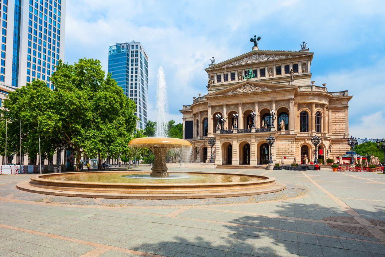 Historische Alte Oper in Frankfurt am Main mit Springbrunnen auf dem Opernplatz an einem sonnigen Tag.