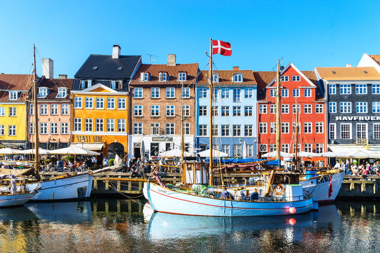 Der berühmte Nyhavn in Kopenhagen mit bunten Häusern, Restaurants und Booten am Hafen.