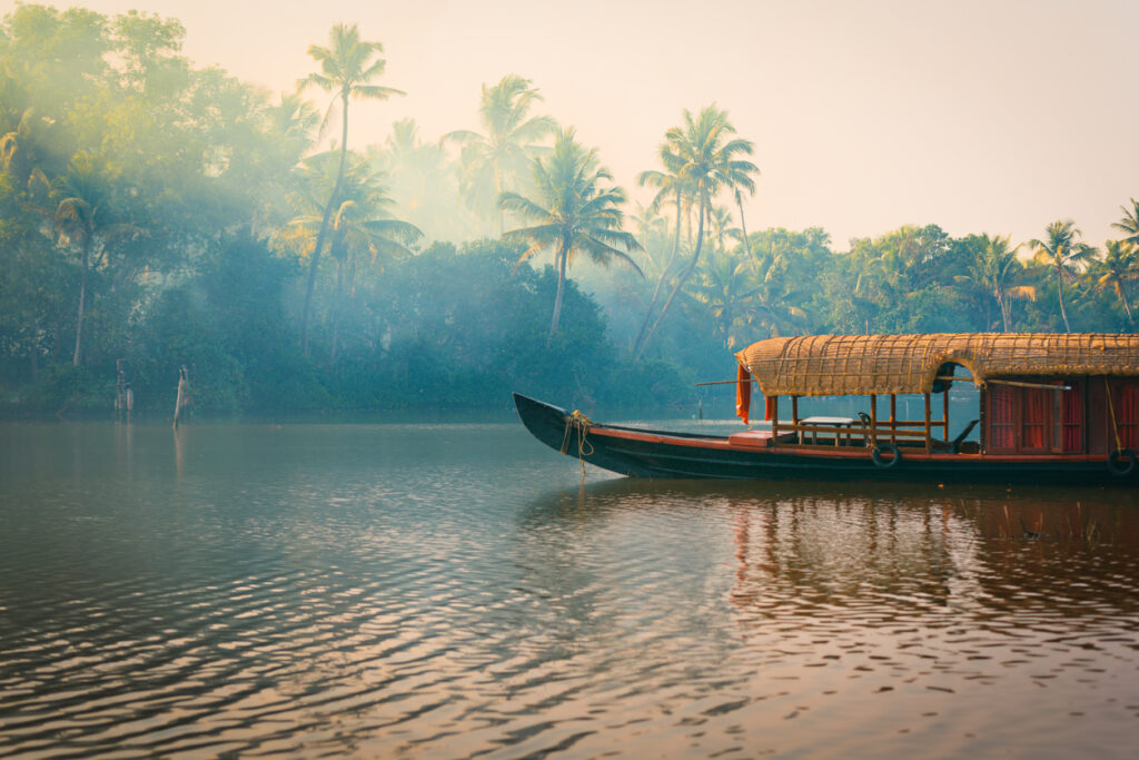 Traditionelles Hausboot auf den Backwaters in Kerala, Indien, umgeben von Palmen und ruhigem Wasser.