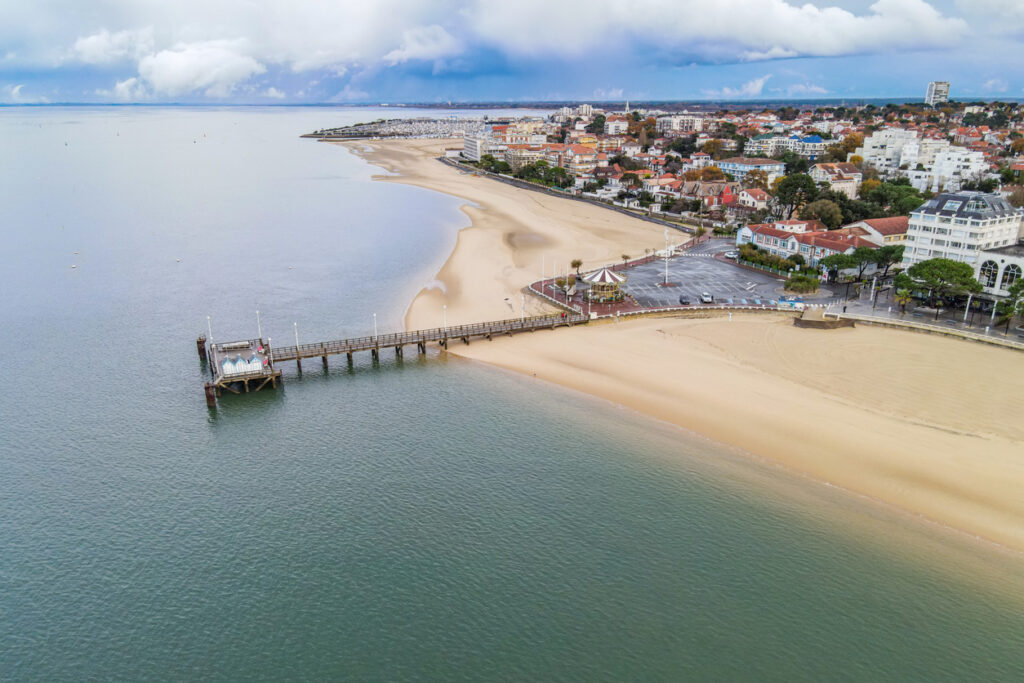 Luftaufnahme der Küstenstadt Arcachon in Frankreich mit Sandstrand, Promenade, Pier und Blick auf die Bucht von Arcachon.