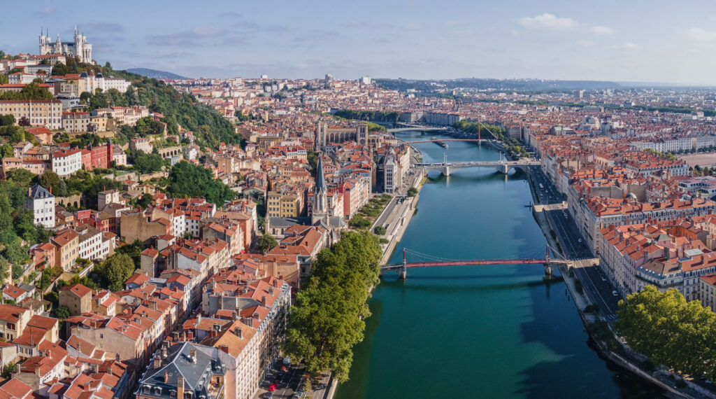 Luftaufnahme von Lyon mit der Saône, mehreren Brücken, den roten Dächern von Vieux Lyon, der Presqu’île und der Basilika Notre-Dame de Fourvière auf dem Hügel.