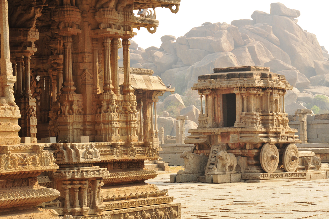 Detailansicht des steinernen Wagens und der kunstvoll verzierten Tempelsäulen im Vijaya-Vittala-Tempel in Hampi, Indien.