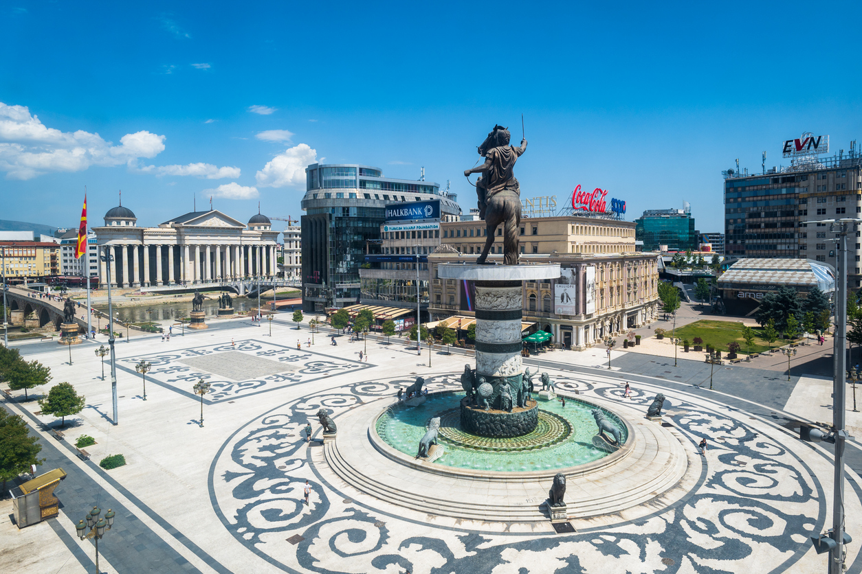 Panorama des zentralen Platzes Makedonien in Skopje mit dem monumentalen Reiterbrunnen „Krieger auf dem Pferd“, Blick auf die historische Steinbrücke über den Vardar und das Archäologische Museum im Hintergrund.