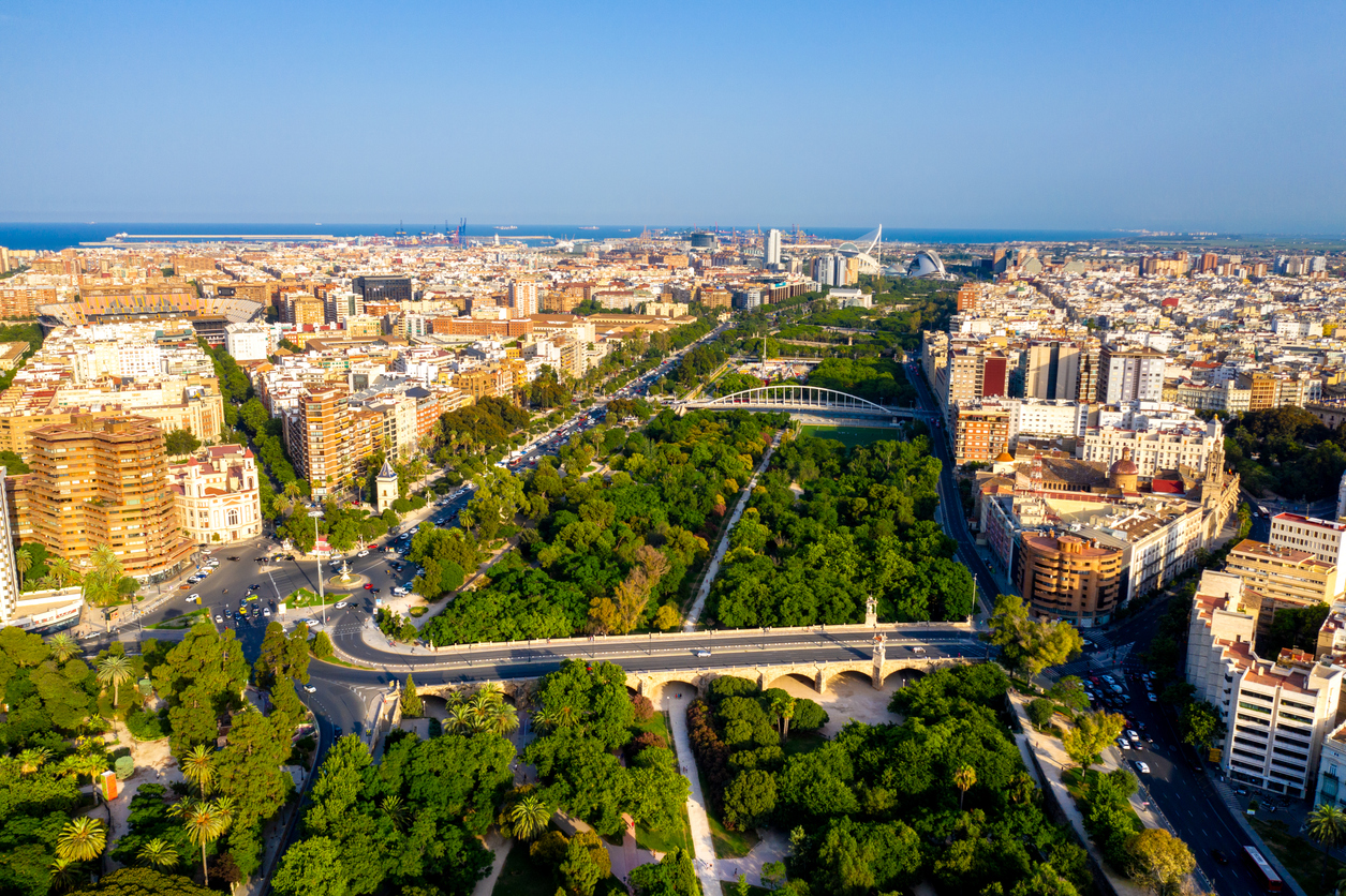 Luftaufnahme von Valencia mit dem grünen Jardín del Turia, mehreren Brücken, Stadtvierteln und der Ciudad de las Artes y las Ciencias bis zum Meer.