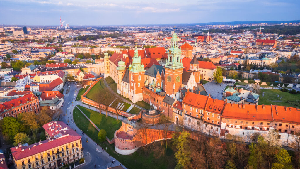 Drohnenaufnahme des Wawel-Schlosses in Krakau mit Blick auf die Altstadt bei warmem Abendlicht.