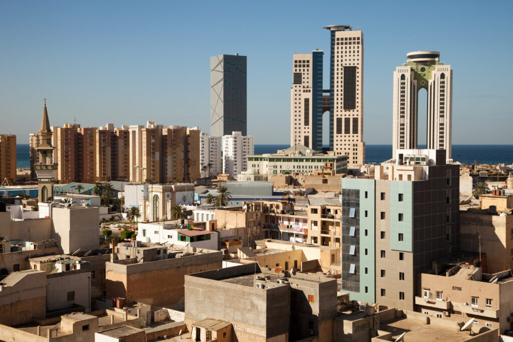 Skyline von Tripolis mit modernen Hochhäusern, Wohnblöcken und Minarett; Mittelmeer im Hintergrund.