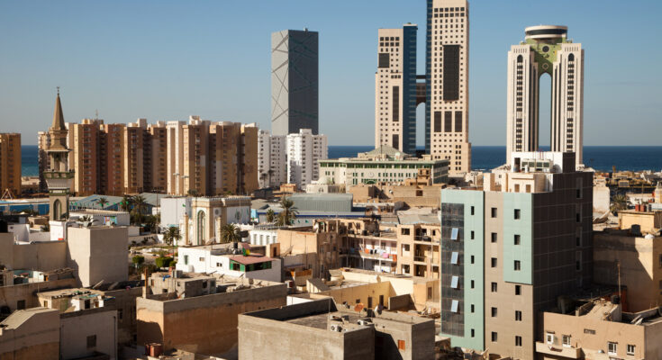 Skyline von Tripolis mit modernen Hochhäusern, Wohnblöcken und Minarett; Mittelmeer im Hintergrund.