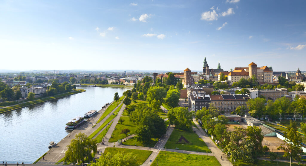 Panorama von Krakau mit der Weichsel, Spazierwegen und dem historischen Wawel-Schloss bei sonnigem Wetter.
