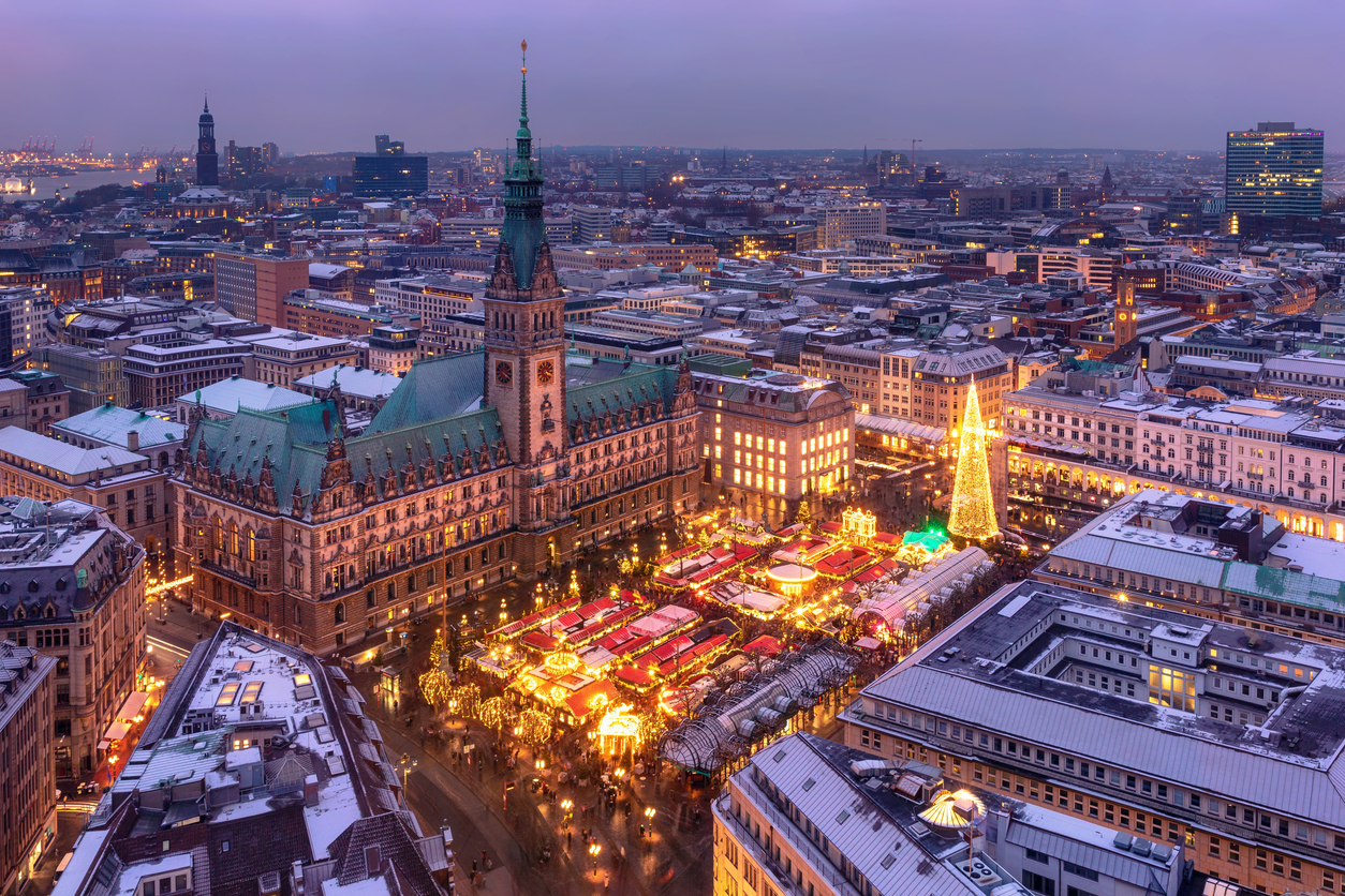 Hamburg, Weihnachtsmarkt am Rathausmarkt mit dicht gereihten, beleuchteten Buden und großem Lichterbaum, Rathaus mit Turm im Hintergrund, winterliche Abendstimmung, Blick von oben