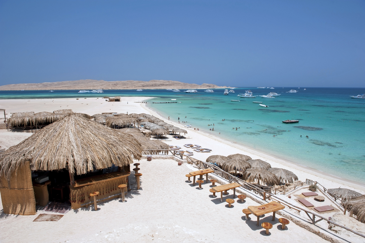 Strand mit Strohhütten und Blick auf das türkisfarbene Meer bei den Giftun-Riffen vor Safaga.