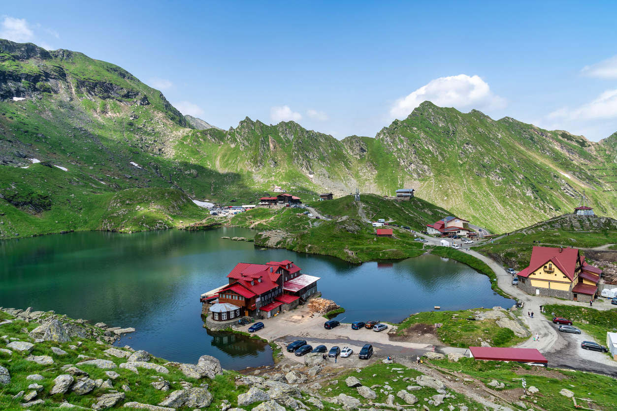 Der Bâlea-See in Rumänien, umgeben von den majestätischen Karpaten, mit Berghütten und klarer Spiegelung im Wasser.