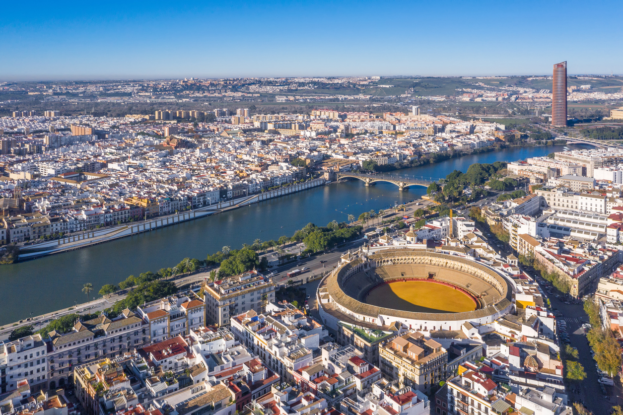 Sevilla, Luftaufnahme der Plaza de Toros de la Maestranza, runde Arena am Guadalquivir, Uferpromenade, Puente de Isabel II und Torre Sevilla im Hintergrund, klarer Himmel