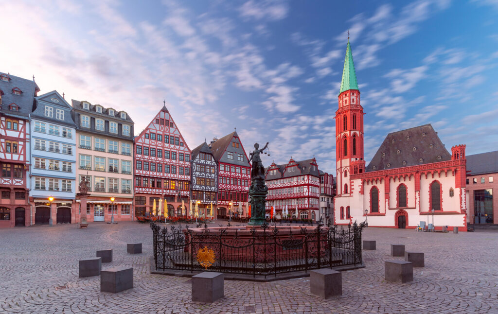 Fachwerkhäuser und Justitia-Brunnen am Römerberg in Frankfurt am Main bei Sonnenaufgang.