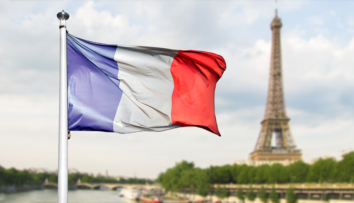 Französische Nationalflagge in Blau, Weiß und Rot weht im Wind vor dem Eiffelturm in Paris.