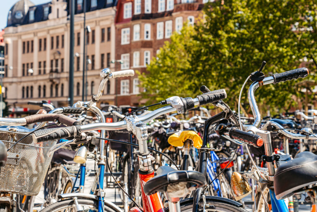 Viele Fahrräder im Zentrum von Malmö, geparkt vor historischen Gebäuden und Bäumen.
