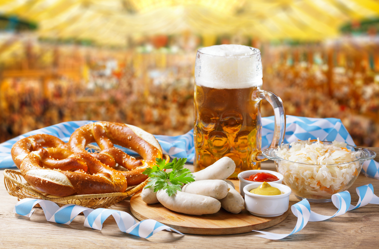 Traditionelle bayerische Brotzeit mit Brezeln, Weißwürsten, Sauerkraut, Senf und einem Bierkrug auf dem Oktoberfest in München.