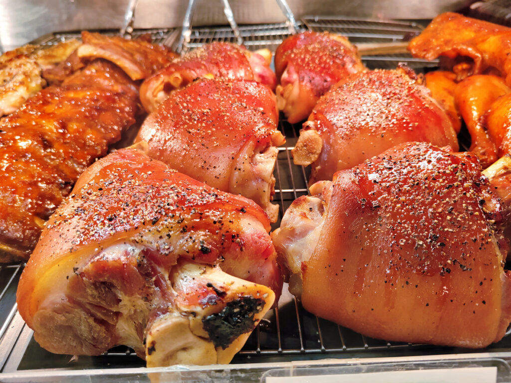 Knusprige, goldbraun gebratene Schweinshaxe mit Gewürzen in der Auslage