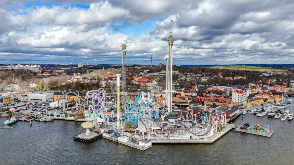 Panoramaaufnahme von Stockholm mit Blick auf den Vergnügungspark Gröna Lund am Wasser und die Stadt im Hintergrund.