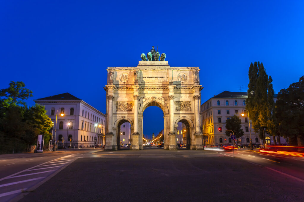 Das Siegestor in München, ein beleuchtetes Wahrzeichen mit Triumphbogen und Quadriga, am Abend.