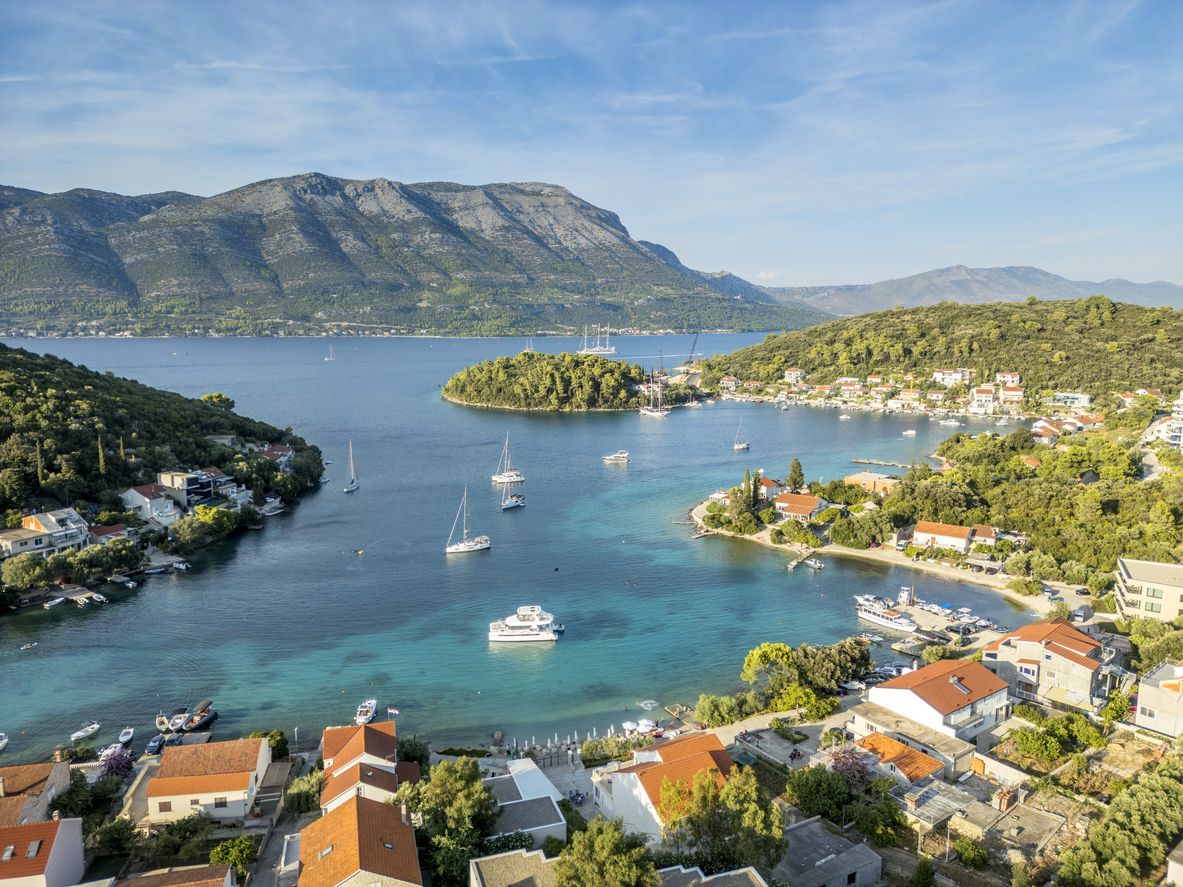 Luftaufnahme von Korčula mit türkisfarbenen Buchten, Inselchen, Segelbooten und roten Dächern vor Gebirgskulisse