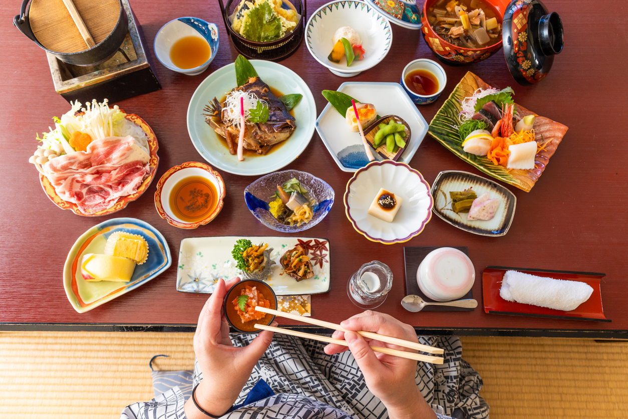 Traditionelles japanisches Kaiseki-Menü mit vielfältigen Gerichten wie Sashimi, gegrilltem Fisch, Gemüse, Suppe und Reis in kunstvoll arrangierten Schalen.