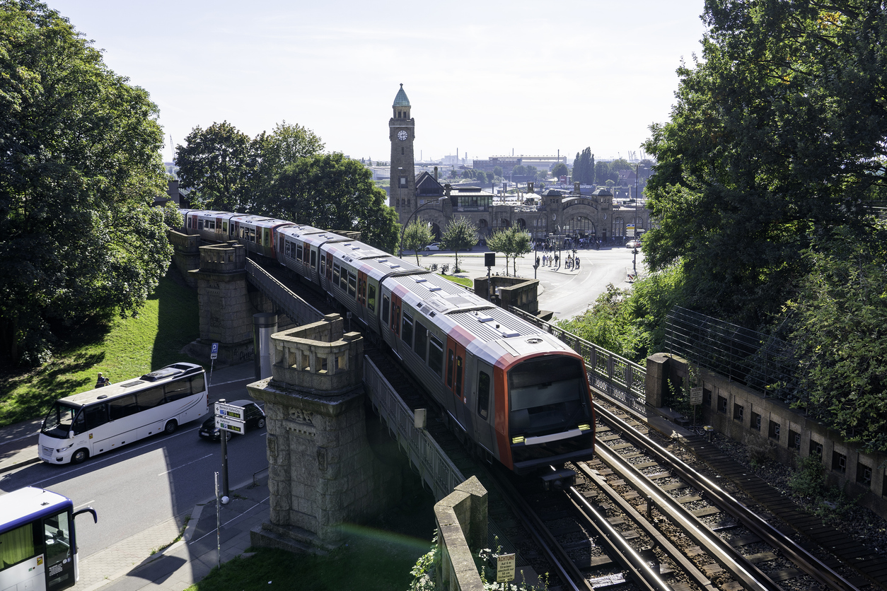 Hamburg, U-Bahn-Zug auf erhöhter Trasse bei den Landungsbrücken, im Hintergrund der Uhrturm der St.-Pauli-Landungsbrücken, Bäume und Straßenverkehr bei Sonne